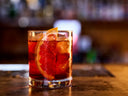 Negroni cocktail with ice and a grapefruit slice served in a glass on a bar counter