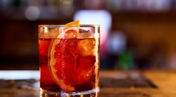 Negroni cocktail with ice and a grapefruit slice served in a glass on a bar counter