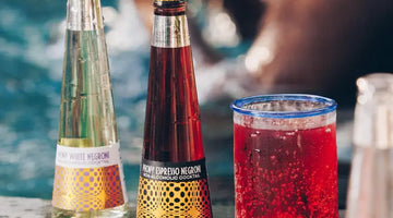 Alcohol-free cocktail bottles beside a fizzy red drink by the pool