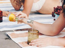 No alcohol cocktail being poured from a Phony White Negroni bottle during a poolside picnic