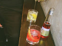 Phony Negroni served in a glass with citrus garnish beside its bottle on a dark bar surface