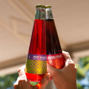 Negroni and Amaro Falso non-alcoholic cocktail bottles being held up together for a toast.