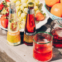 No alcohol espresso Negroni bottles on a picnic table with fresh fruit and colorful summer drinks.