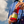 Load image into Gallery viewer, No alcohol negroni bottle held in hand against a blue sky, with the person wearing a blue striped shirt.

