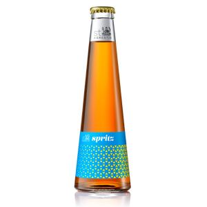 Alcoholic spritz in a tall glass bottle with orange liquid and blue label featuring yellow geometric patterns.